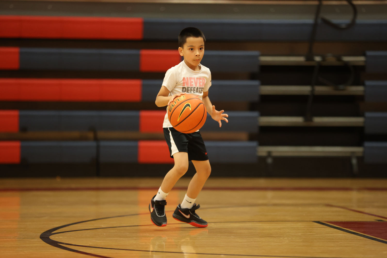 Young camper dribbling down the court